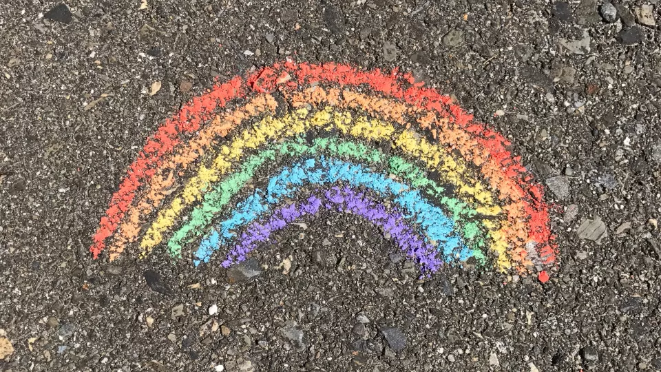 En regnbåge målad med krita på marken. Foto. 