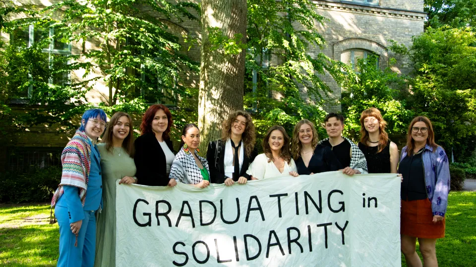 Mastersstudenter med banderoll där der står "graduating in solidarity"