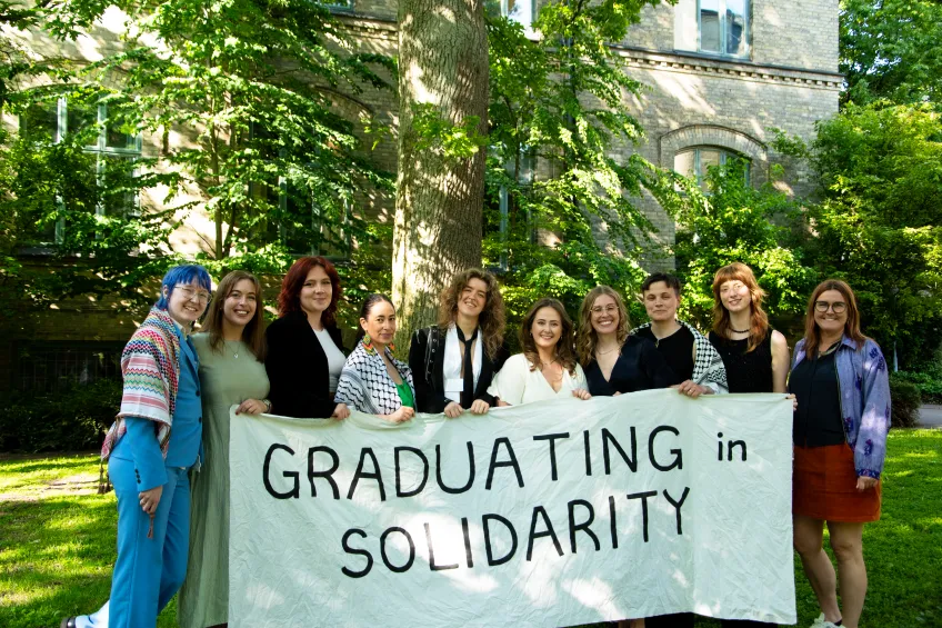 Mastersstudenter med banderoll där der står "graduating in solidarity"